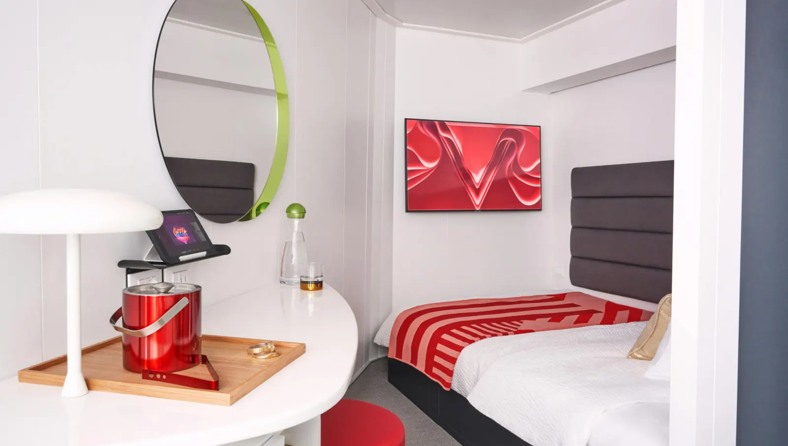 Compact Virgin Voyages cabin with bed, desk and lamp