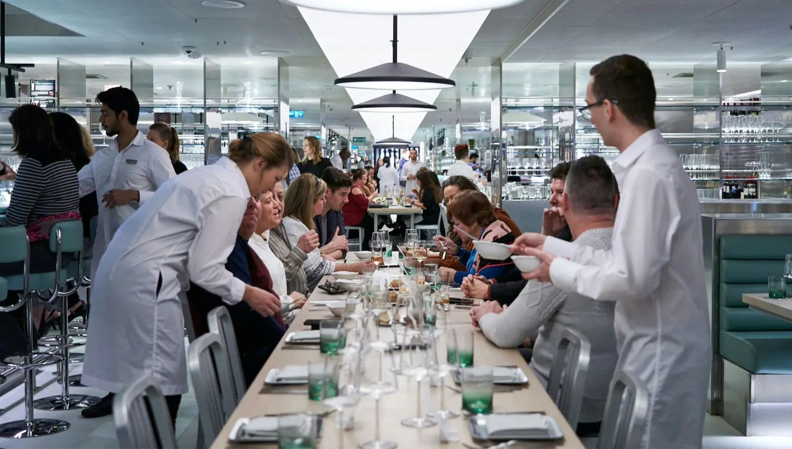 Guests dining at a shared table in a Virgin Voyages restaurant