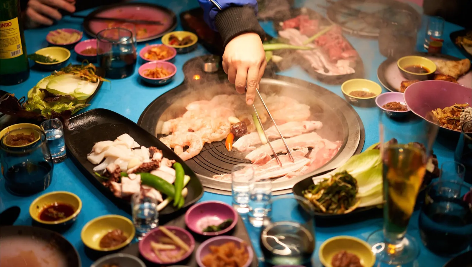 Server grilling Korean barbecue at Gunbae on a Virgin Voyages ship